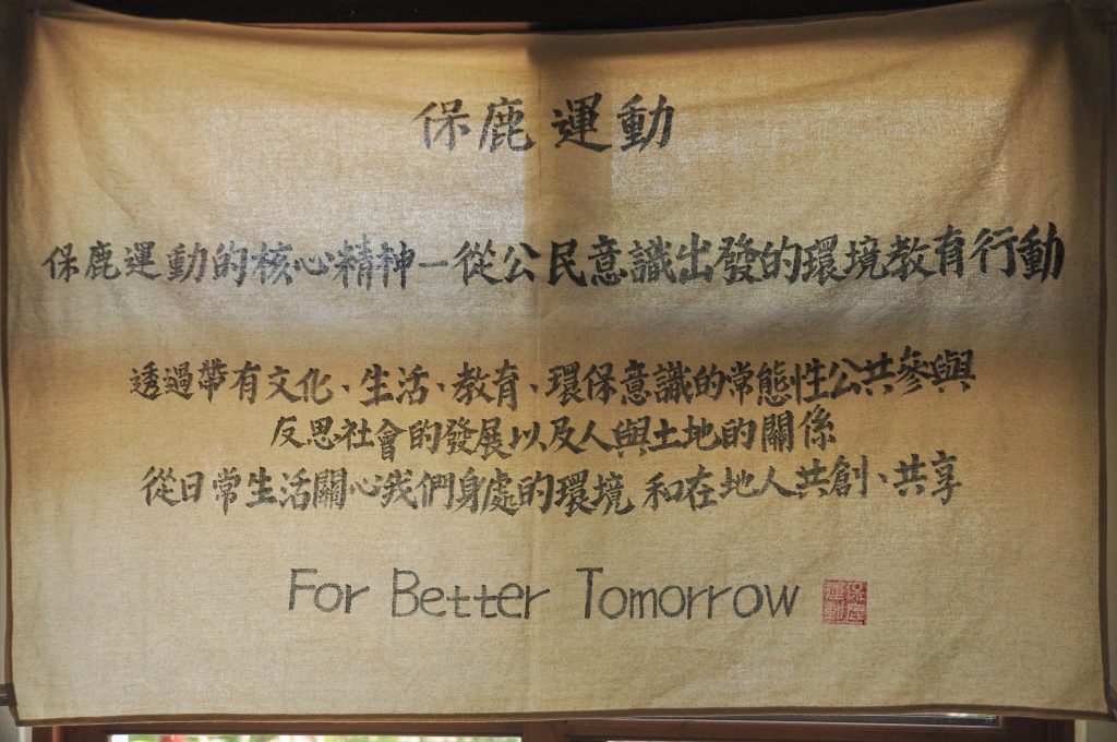 一塊米白色的布吊在窗戶上，有光透出，布上頭字用書法字體寫出